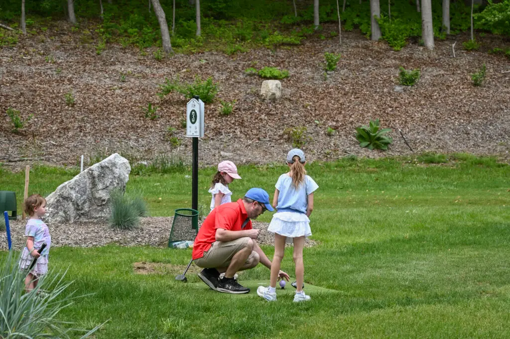 Father playing park golf with his daughters at 1Club in Vernon Valley, New Jersey, on a warm summer day.