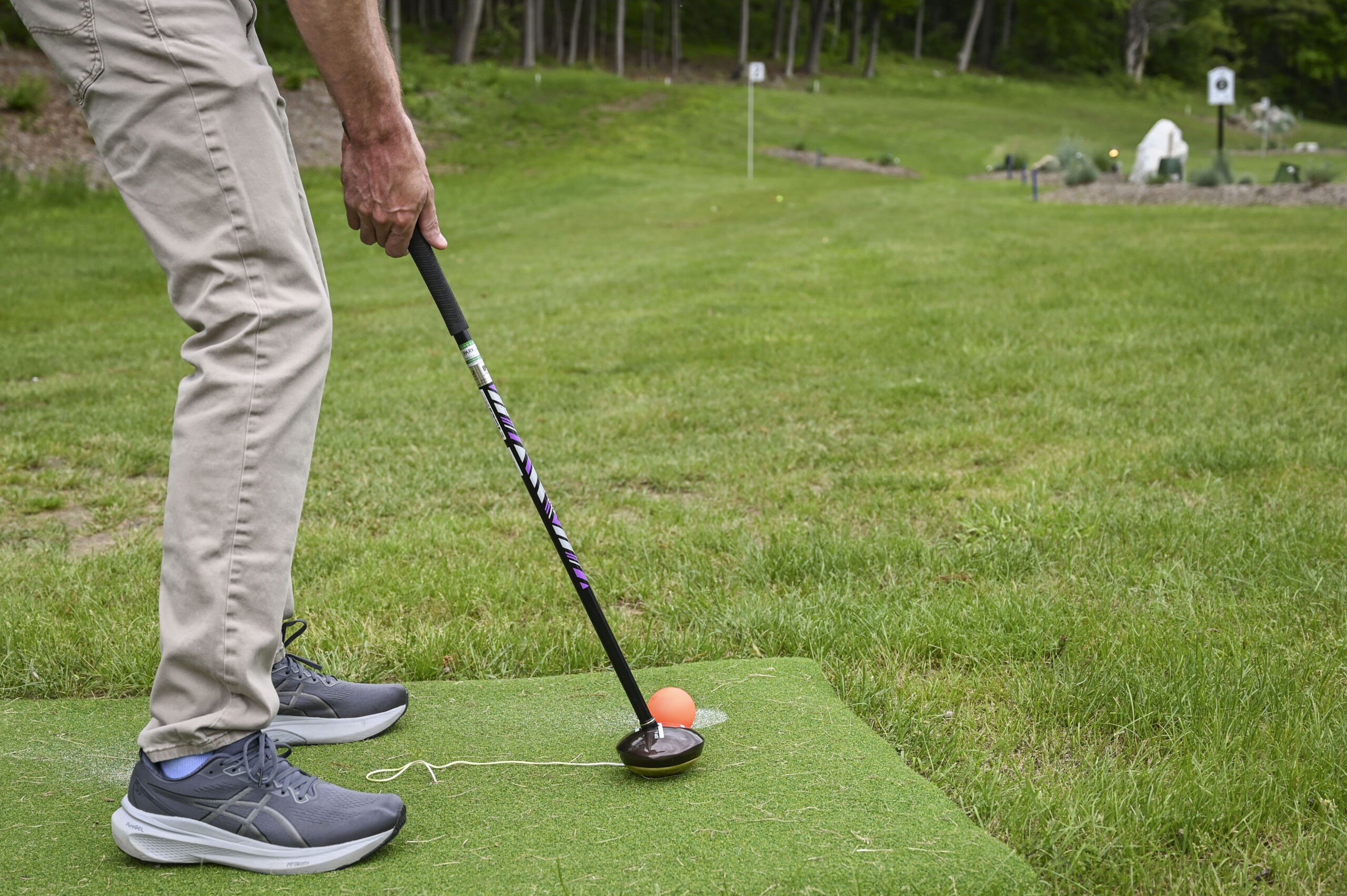Man playing park golf at 1Club Vernon, surrounded by lush green hills and scenic Vernon Valley landscape under a clear sky, a a symbol of health benefits of park golf.