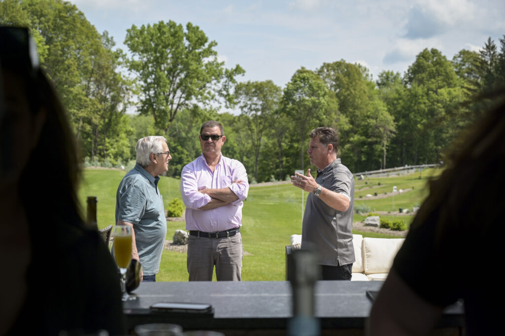 A group of men enjoying drinks before starting their park golf game at 1Club in Vernon, NJ, relaxing and socializing in the outdoor setting before heading onto the course.